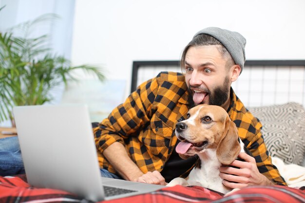 Knappe jonge hipster met zijn hond die thuis op bed rust