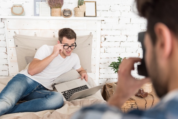 Knappe jonge homoseksuele man poseren voor zijn jonge vriendje met een camera en het nemen van foto's.