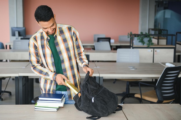 Knappe jonge indiase jongensstudent met boeken en rugzak aan de universiteit onderwijsconcept