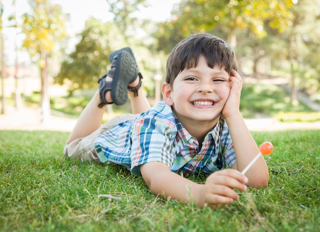 Knappe jonge jongen genieten van zijn lolly buiten op het gras