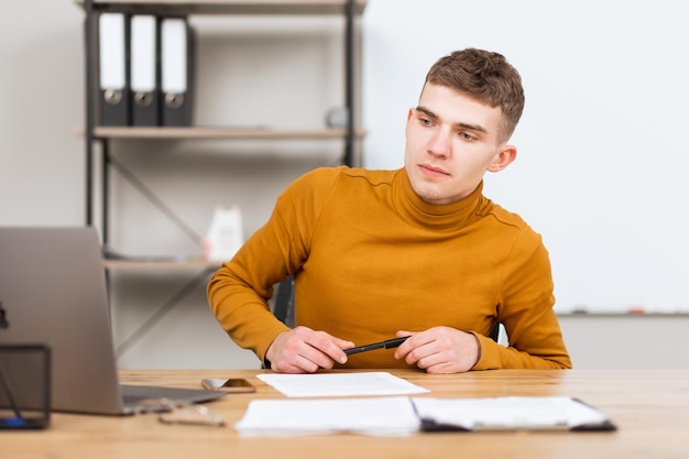 Knappe jonge man aan het werk met documenten op kantoor