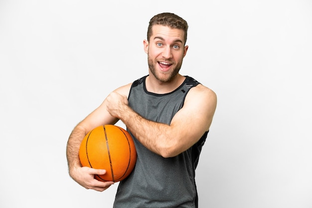 Knappe jonge man die basketbal speelt over een geïsoleerde witte achtergrond die een overwinning viert