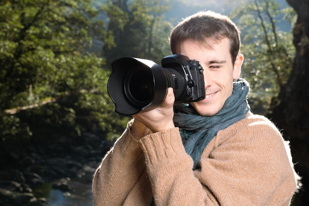 Knappe jonge man die een foto maakt met een DSLR-camera