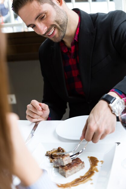 Knappe jonge man die gehaktbrood op een bord in het restaurant serveert.