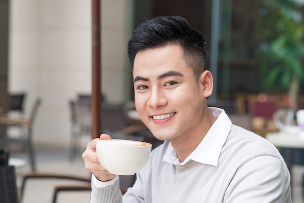 Knappe jonge man die koffie drinkt in de stad