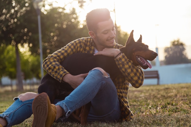 Knappe jonge man die met zijn hond in het park speelt.