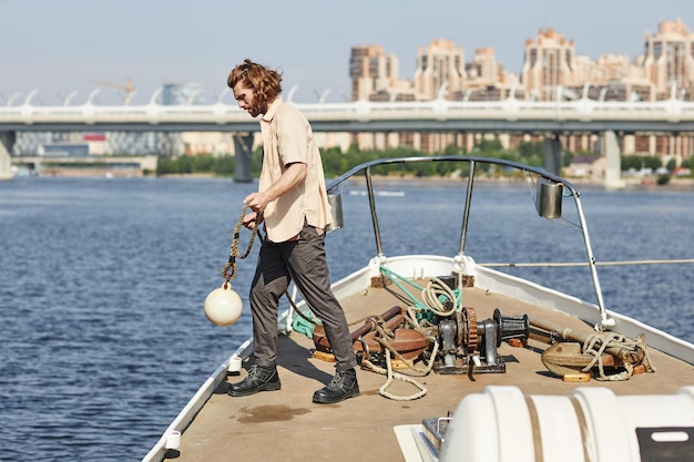 Knappe jonge man die op de boot staat en lijn in het water gooit