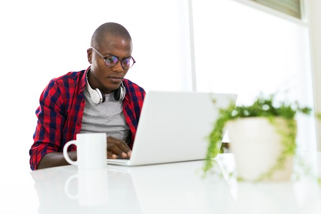 Knappe jonge man die zijn laptop thuis gebruikt.