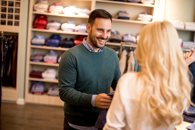 Knappe jonge man het kopen van broeken met zijn vrouw in de mode winkel