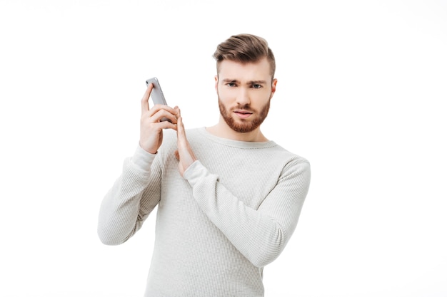 Knappe jonge man in een witte trui praten aan de telefoon