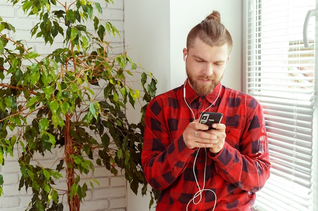 Knappe jonge man in hoofdtelefoon met mobiele telefoon