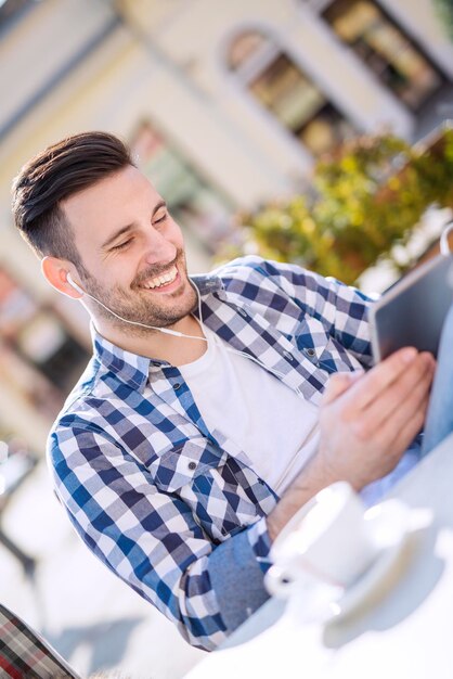 Foto knappe jonge man koffie drinken en luisteren naar muziek op een slimme telefoon.