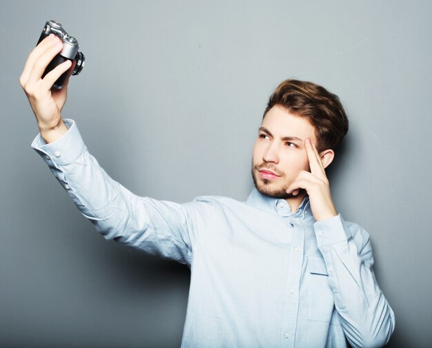 Knappe jonge man met camera en selfie maken