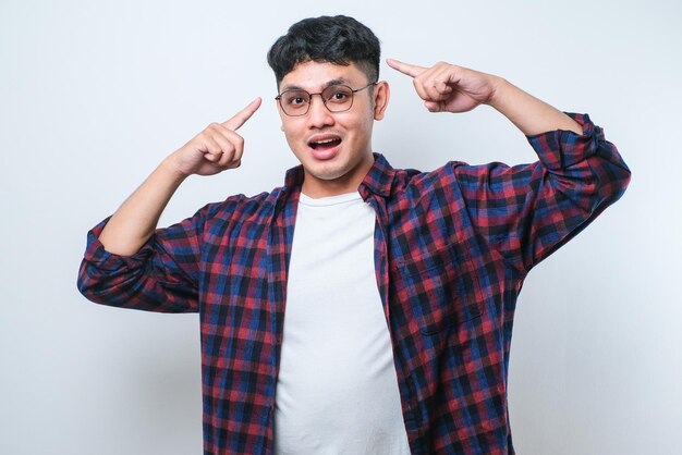 Knappe jonge man met een casual shirt glimlachend wijzend naar het hoofd met de vinger van de hand