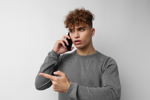 Knappe jonge man met een telefoon in de hand communicatie geïsoleerde achtergrond