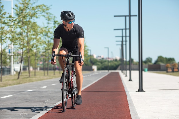 Knappe jonge man met helm en zonnebril op een fiets