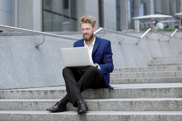 Knappe jonge man met laptop buitenshuis