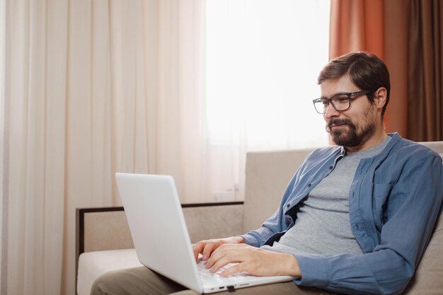Knappe jonge man met laptopcomputer thuis