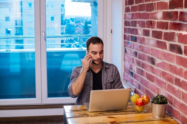 Foto knappe jonge man met mobiele telefoon en laptop