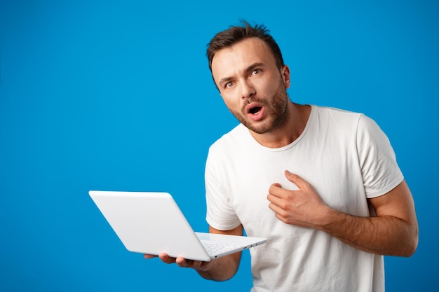 Knappe jonge man met zijn laptop tegen blauwe achtergrond