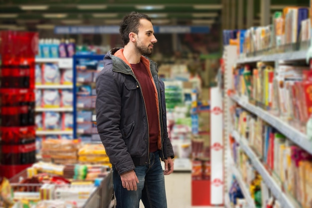 Knappe jonge man winkelen voor groenten en fruit in de productieafdeling van een supermarkt Supermarkt ondiep diep van het veld