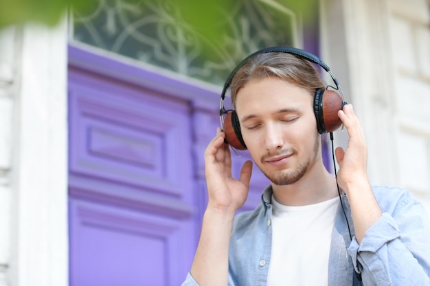 Knappe jonge mens die aan muziek in openlucht luistert