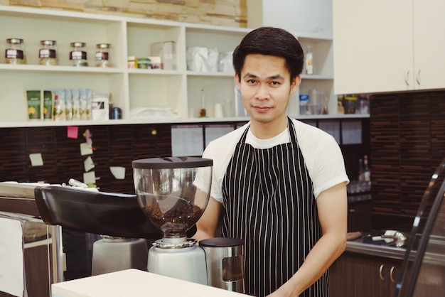 Knappe jonge mensen Aziatische barista die koffie met koffiemachine maken bij tegenkoffiewinkel.