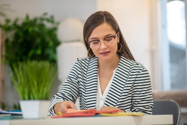 Knappe jonge ontwerper die verschillende voorbeelden bekijkt terwijl ze zich concentreert op haar werk