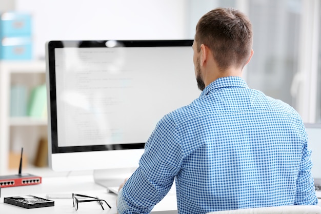 Foto knappe jonge programmeur die in bureau werkt