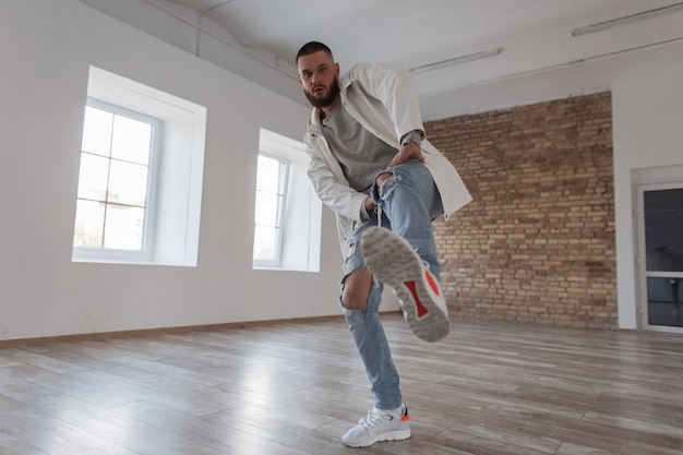 Knappe jonge stijlvolle aantrekkelijke kerel danser in trendy kleding dansen in de studio