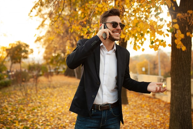 Knappe jonge stijlvolle mannelijke zakenman gelukkig en glimlachend praten aan de telefoon