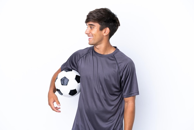 Knappe jonge voetballer man geïsoleerd op een witte achtergrond op zoek naar kant