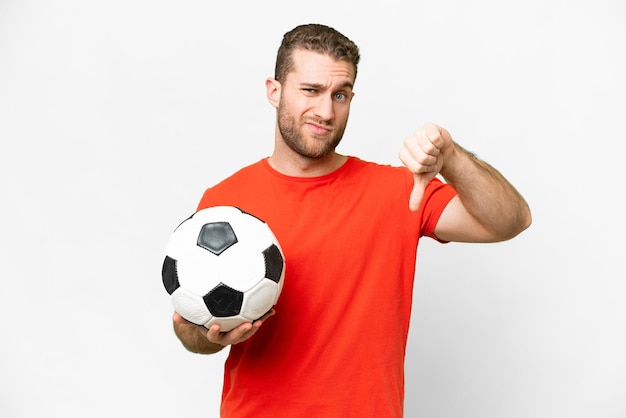 Knappe jonge voetballer man over geïsoleerde witte achtergrond met duim naar beneden met negatieve uitdrukking