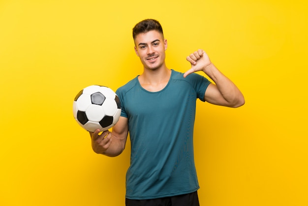 Knappe jonge voetbalstermens over geïsoleerde gele trots en zelf-tevreden muur