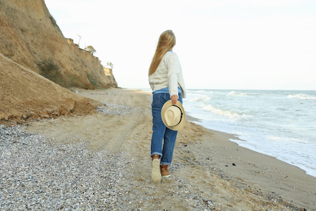 Knappe jonge vrouw met hoed op zandstrand