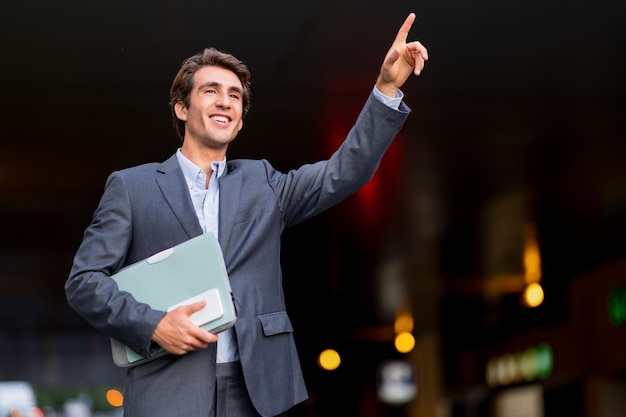 Knappe jonge zakenman die een taxi op straat haalt