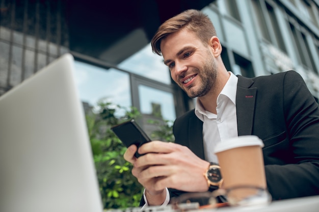 Knappe jonge zakenman die koffie heeft en sms't