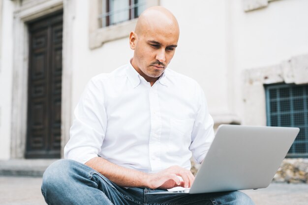 Knappe jonge zakenman in een wit overhemd dat met laptop werkt