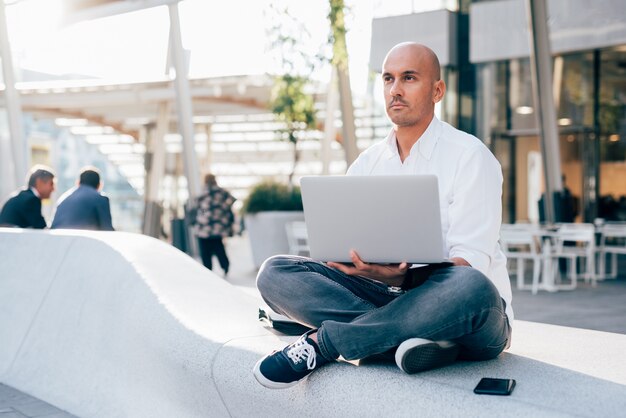 Knappe jonge zakenman in een wit overhemd dat met laptop werkt