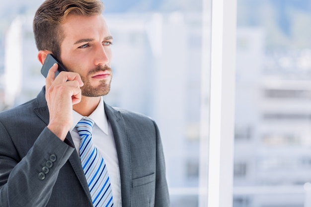 Knappe jonge zakenman met behulp van de mobiele telefoon