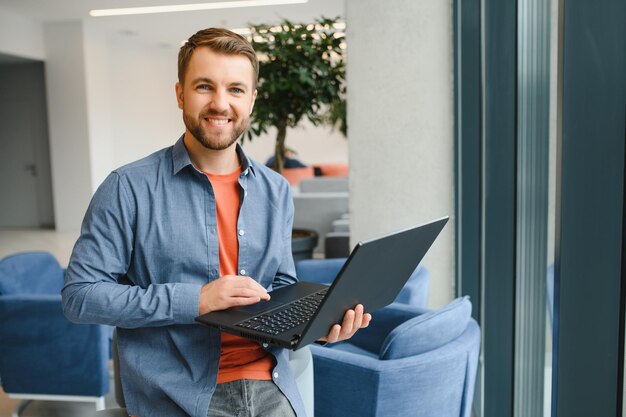 Knappe jonge zakenman met behulp van een laptop in het café