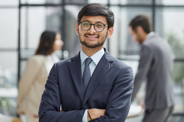 Knappe jonge zakenman met een bril die vol vertrouwen op kantoor staat