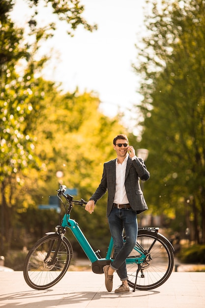 Knappe jonge zakenman op de ebike die mobiele telefoon met behulp van