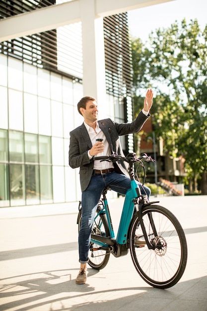 Knappe jonge zakenman op de ebike met afhaalmaaltijden koffiekopje