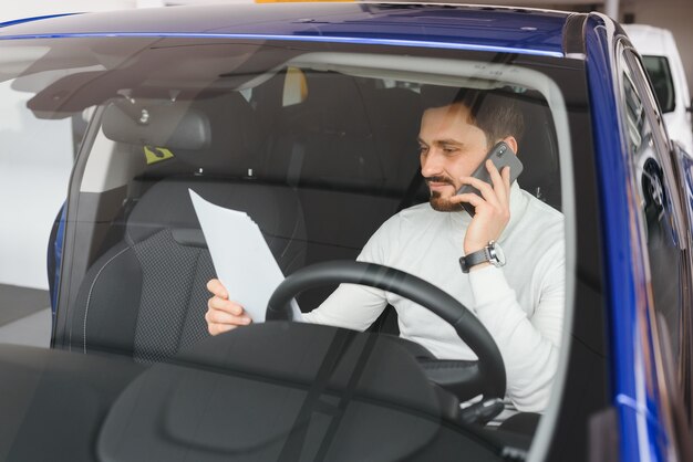 Knappe jonge zakenman praten over zijn slimme telefoon en lachend zittend op de voorstoel