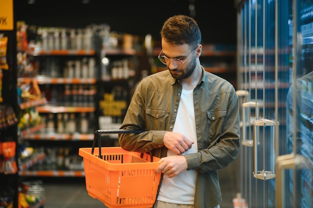 Knappe jongeman die eten kiest in de supermarkt