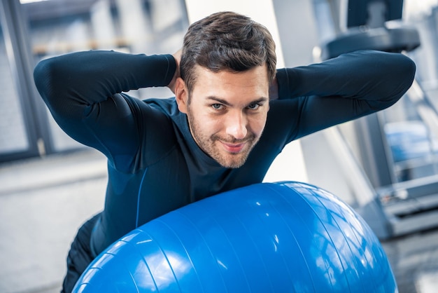 Knappe jongeman die traint op een fitnessbal in de sportschool