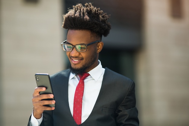 Knappe jongeman in pak en bril met telefoon