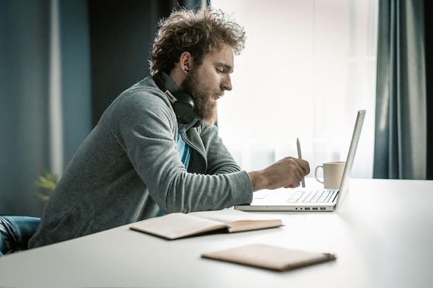 Knappe jongen bestelt goederen in de online winkel vanaf zijn laptop man kiest thuisbezorging uit