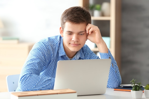 Knappe jongen die thuis op de computer werkt